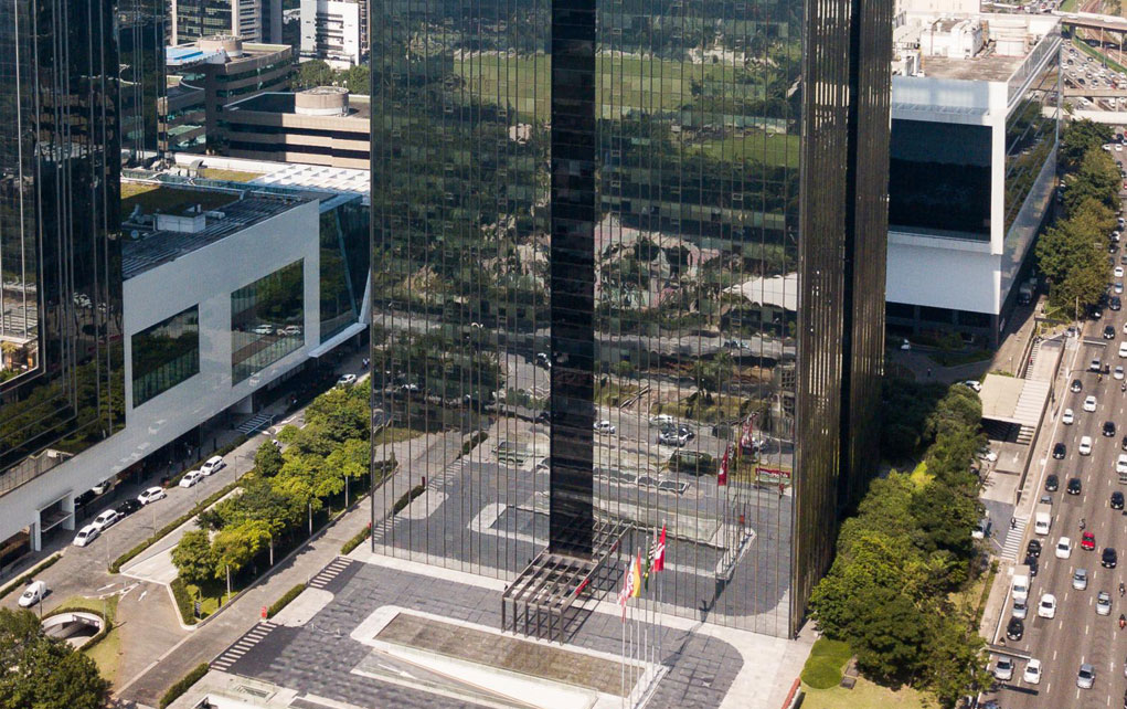 prédio alto e espelhado com árvores na frente